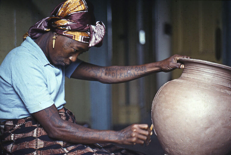 Ladi Kwali, a Nigerian female potter, works on a ceramic vessel
