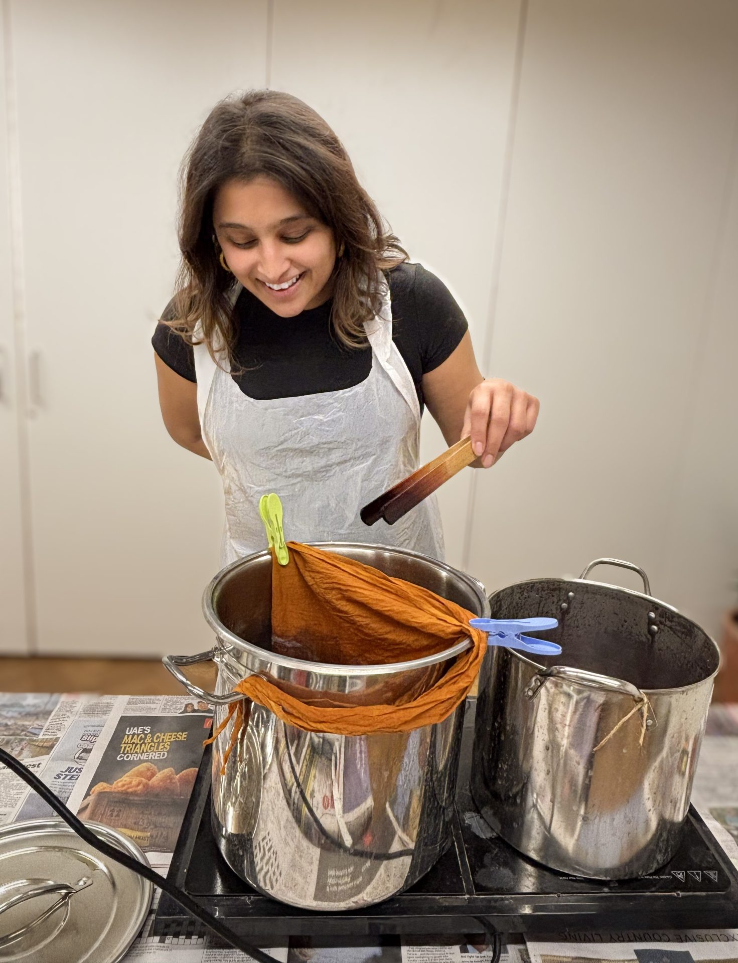 Participant dips an organic cotton scarf into a plant‑based dye pot in a London natural‑dye workshop